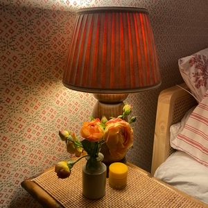 Guest bedroom ideas: a bedside table with a lamp, a small vase of orange roses and a candle